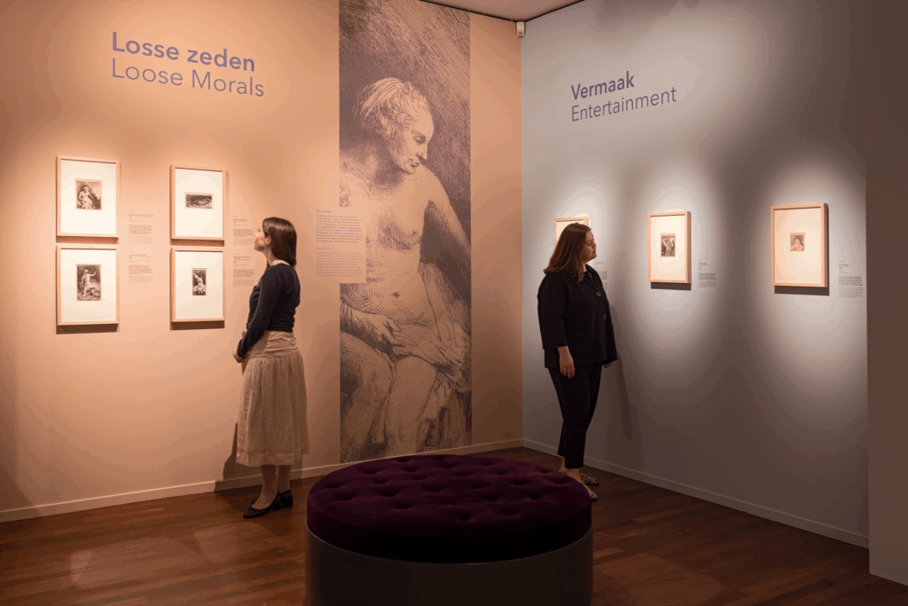 2 bezoekers kijken naar etsen uit de tentoonstelling Rembrandt & Amsterdam